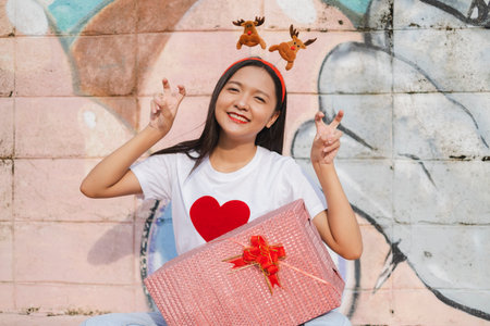 A beautiful girl wear Christmas hat hold present on colorful background.の写真素材