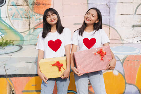 Two happy young girl with present box on colorful background.Asian girl.の写真素材