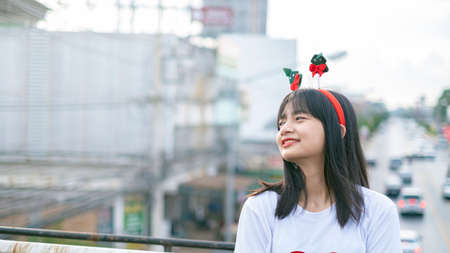 Happy young girls wear Christmas hat on city view background.の写真素材