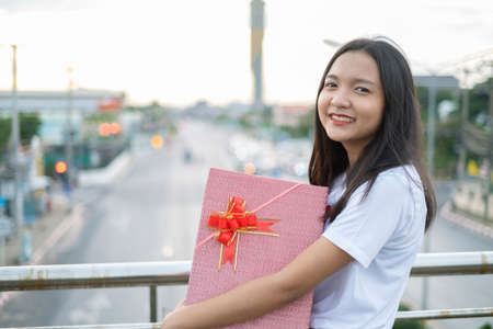 Happy young girl hold gift box on city view background.の写真素材