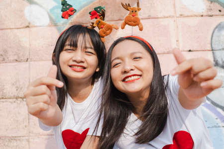 Happy two girl wear christmas hat on colorful background.の写真素材