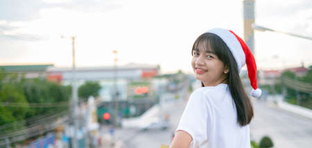 Happy young girls wear Christmas hat on city view background.の写真素材