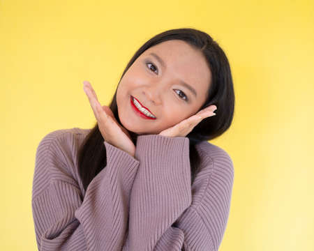 Happy young girl hold red paper , Asian girl wear brow sweater on yellow background.の写真素材