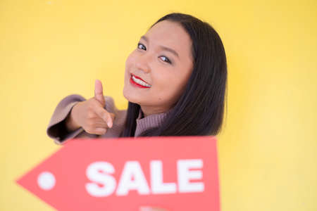 Happy young girl hold red paper , Asian girl wear brow sweater on yellow background.の写真素材