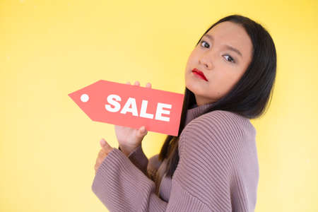 Happy young girl hold red paper , Asian girl wear brow sweater on yellow background.の写真素材