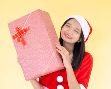Happy Santa claus girl wear boot hold present box on yellow background.の写真素材