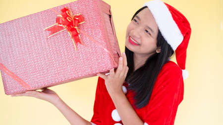 Happy Santa claus girl wear boot hold present box on yellow background.の写真素材