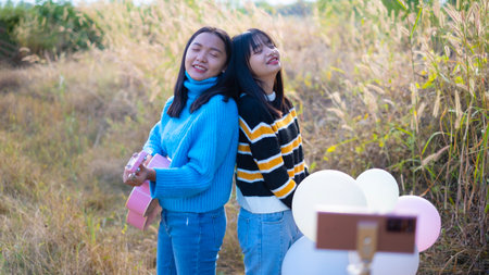 Two happy young girl playing guitar and make vdo at the meadow.の写真素材