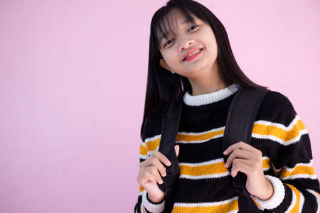 Happy young girl with backpack on pink background.の写真素材