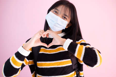 Student young girl wear mask on pink background.の写真素材