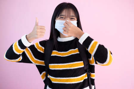 Student young girl wear mask on pink background.の写真素材