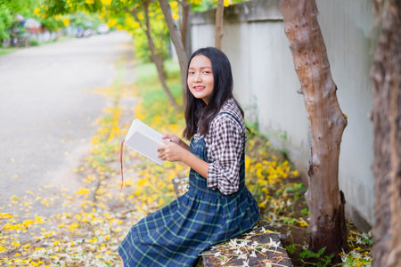 Student young girl hold book under the beautiful tree.の写真素材