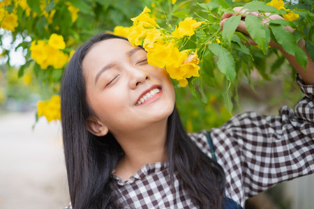 Beautiful young girl sitting under the tree with gift box.の写真素材