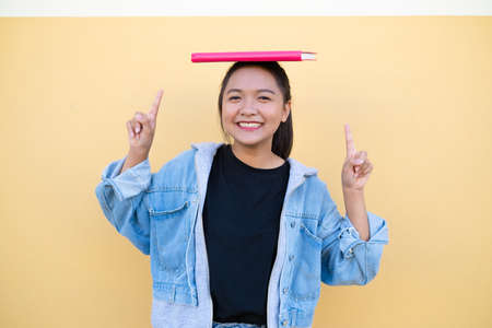 Happy student young girl with pink book on brown background.の写真素材
