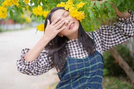 Beautiful young girl sitting under the tree with gift box.の写真素材