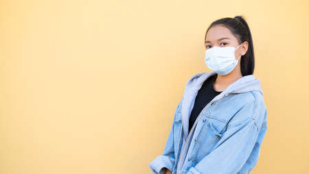 Portrait happy young girl wear mask and jacket jean on orange background.