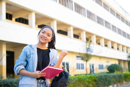 Smile girl hold pink book standing on building background,Back to school.の写真素材