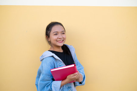 Happy student young girl with pink book on brown background.の写真素材