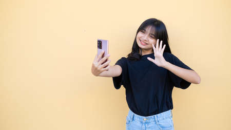 Portrait young girl use mobile on orang baclground.