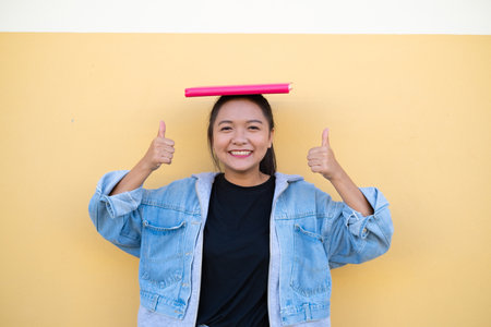 Happy student young girl with pink book on brown background.の写真素材