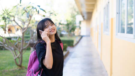 Beautiful young girl useing smart phone at school,Asian girl,Orange background.の写真素材