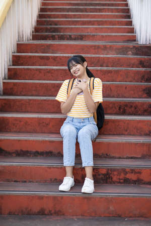 Happy girl use smartphone sitting on stairs at school,Back to school.の写真素材