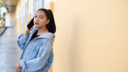 Young girl talking on moobile standing at school,Asian girl.の写真素材