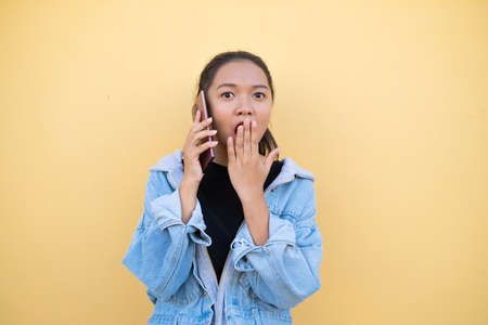 Portrait young girl wear jacket jean and use mobile on brown background.の写真素材