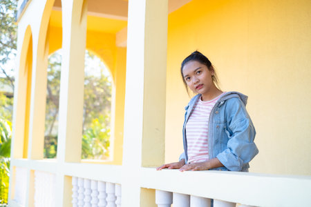 Happy young girl standing at building yellow background.の写真素材