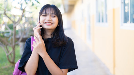 Beautiful young girl useing smart phone at school,Asian girl,Orange background.の写真素材