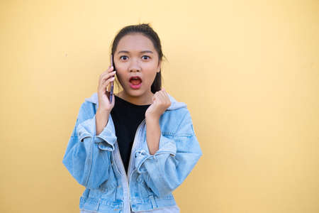 Portrait young girl wear jacket jean and use mobile on brown background.の写真素材