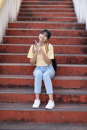 Happy girl use smartphone sitting on stairs at school,Back to school.の写真素材