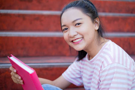 Smile young girl hold pink book sitting at school,Asian girl.の写真素材