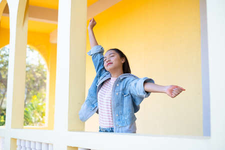Happy young girl standing at building yellow background.の写真素材