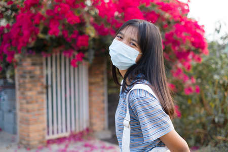Portrait Young Asian girl wear mask outdoor, beautiful flower background.の写真素材