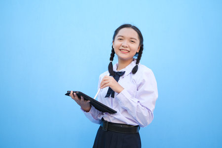 School girl holding tablet on blue background.の写真素材
