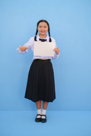 School girl holding billboard on blue background.の写真素材