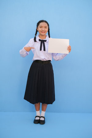 School girl holding billboard on blue background.の写真素材