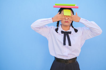 Student with book and small note paper on blue background.の写真素材