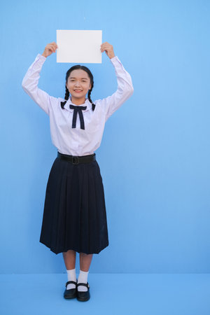 School girl holding billboard on blue background.の写真素材