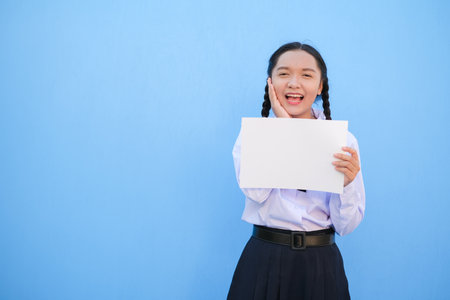 School girl holding billboard on blue background.の写真素材