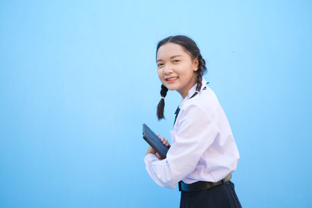 School girl holding tablet on blue background.の写真素材
