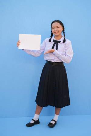 School girl holding billboard on blue background.の写真素材