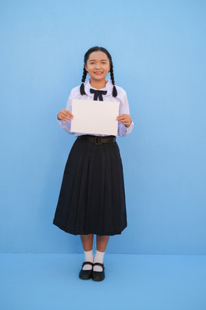 School girl holding billboard on blue background.の写真素材