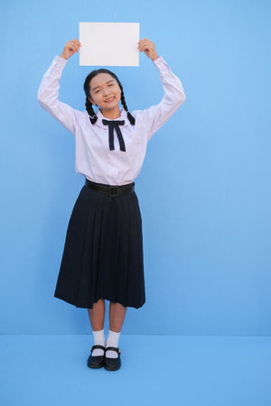 School girl holding billboard on blue background.の写真素材