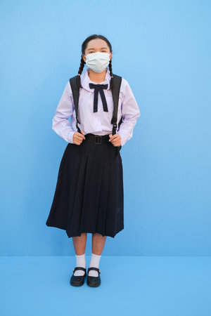School girl wear mask on blue background,Back to school.の写真素材