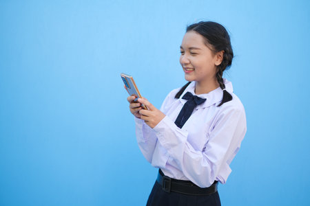 Student young girl useing smart phone on blue background.の写真素材