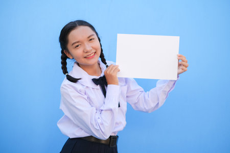 School girl holding billboard on blue background.の写真素材