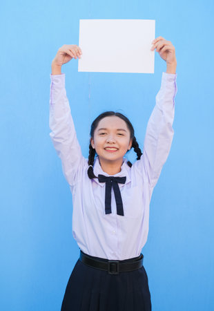School girl holding billboard on blue background.の写真素材