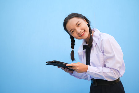 School girl holding tablet on blue background.の写真素材